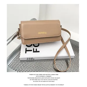 Detail view of the khaki matte leather baguette bag resting on an elegant white book