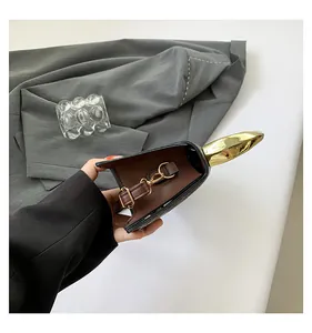 Detail of crocodile pattern leather bag featuring abstract golden metal hardware trim