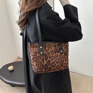 Close-up of leopard print tote bag fabric with black leather strap and gold rivet details