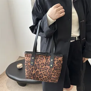Detail of leopard print tote bag with black leather handles and gold rivet accents