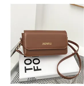 Detail view of the brown leather baguette bag with gold lettering and metal hardware
