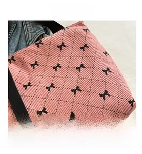 Detail der rosa Cord-Tragetasche mit schwarzen Schleifenprint und gesteppter Textur