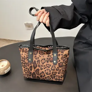Close-up of leopard print tote bag featuring black handles and gold rivet accents