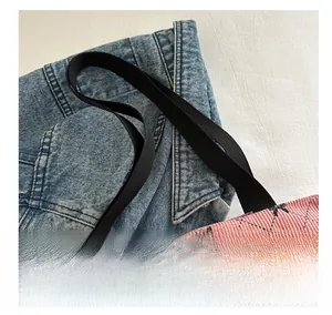 Detail eines schwarzen Stoffgriffs an einer rosa Cord-Tasche mit Schleifenmuster
