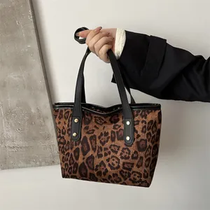 Detailed view of leopard print tote bag with black leather handles and gold rivet accents