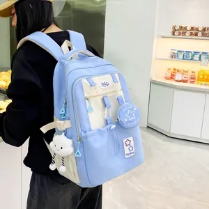 Side view of a blue and beige school backpack with multiple compartments and cute pendants