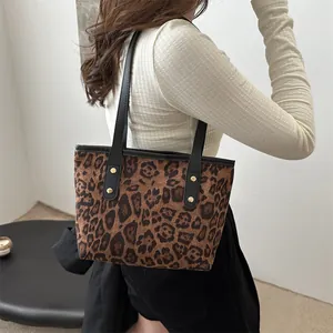 Detailed close-up of leopard print tote bag with black leather straps and gold rivets