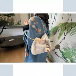 Close-up of beige plush tote bag with brown leather strap and cute biscuit pendant