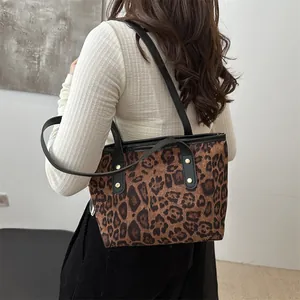 Detailed view of leopard print tote bag with black leather handles and gold rivet accents