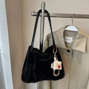 Detail of black faux fur tote bag with plush bear charm and sleek PU shoulder straps