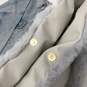 Close-up of beige lychee leather tote with grey faux fur trim and gold magnetic buckles