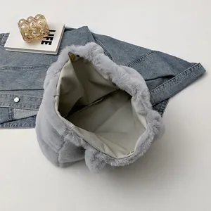 Detail of grey plush tote bag showing the magnetic buckle and spacious leather interior
