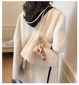 Detail of soft plush crossbody bag in cream faux fur with cute decorative charms