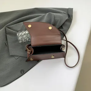Dark brown faux leather shoulder bag with gold magnetic clasp and minimalist saddle design