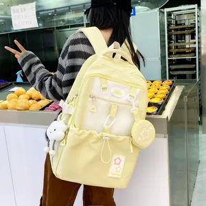 Close-up of yellow canvas backpack features multiple pockets and cute plush pendants