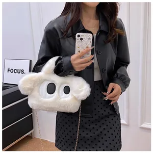 Détail du sac en peluche blanche avec yeux de chien, chaîne en métal et tenue noire chic