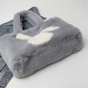 Detail of dark grey faux fur tote bag with white heart pattern on denim background