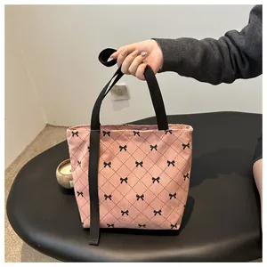 Detail der rosa Cord-Tragetasche mit schwarzen Schleifenmustern und robusten Gurtgriffen