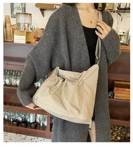 Detailed view of beige nylon crossbody bag featuring stylish pleated drawstring pocket design