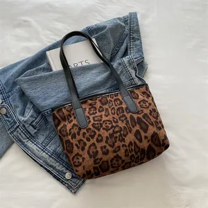 Detailed top view of a leopard print tote bag placed on a denim jacket with an arts book