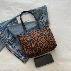 Detail of leopard print tote bag featuring black handles and gold rivet accents on fabric
