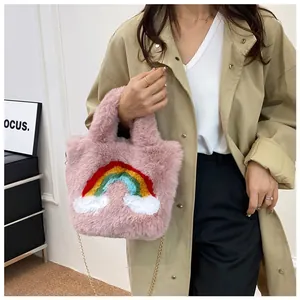 Detailed macro view of a pink plush handbag with rainbow embroidery and gold metal chain