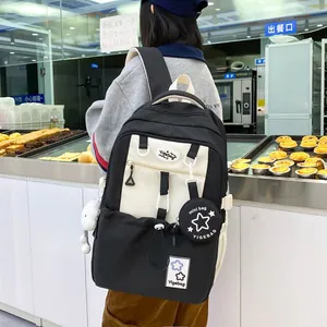 Detail of high-capacity black and white backpack with plush pendant and mini pouch