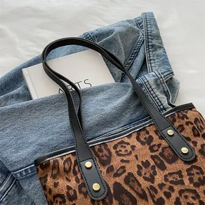 Close-up of leopard print tote bag with black straps and vintage gold rivet details