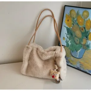 Detail of plush cream tote bag with leather handles and cute bear charm in cozy setting