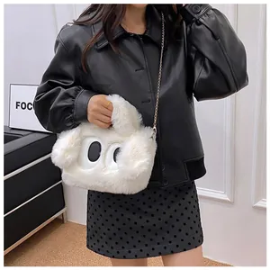 Détail d'un sac à main en peluche blanche avec yeux brodés et chaîne dorée