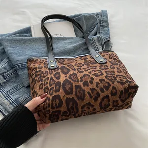 Close-up of leopard print tote bag with black handles and golden rivet detailing