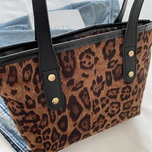 Detail of leopard print tote bag with black faux leather trim and golden metal rivets