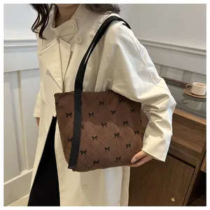 Detailaufnahme einer braunen Cord-Tragetasche mit Schleifenmuster, getragen zum Trenchcoat