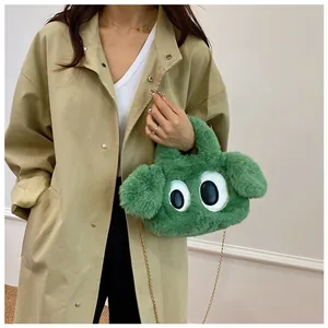 Détail du sac chiot en peluche verte avec bandoulière chaîne sur un trench-coat beige