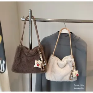 Detail of plush faux fur tote bags in brown and beige with cute cartoon doll pendants