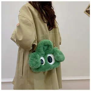 Détail du sac en peluche verte avec yeux de dessin animé et chaîne dorée