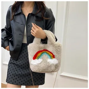 Detail of plush cream tote bag featuring colorful rainbow patch and gold chain strap