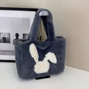 Detailed view of dark grey plush tote bag with white bunny patch on a display stand