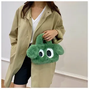 Détail du sac en peluche verte avec de grands yeux de dessin animé et chaîne dorée