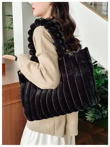 Détail du sac cabas en fausse fourrure noire avec rayures verticales et anses à pompons