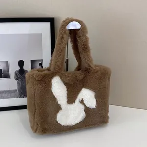 Detail of a brown plush tote bag with a white rabbit silhouette on a display stand