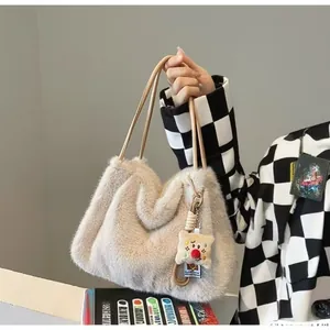 Detail of a beige faux fur tote bag with slim straps and a cute cartoon bear charm
