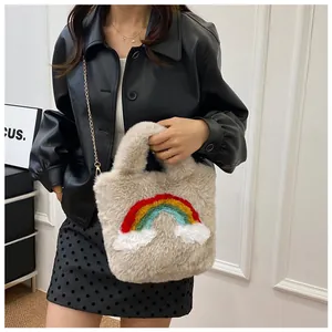 Detail of plush beige handbag with rainbow embroidery and gold chain strap on model