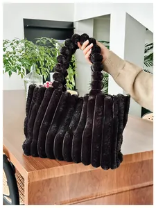 Détail d'un cabas en fausse fourrure noire avec rayures et poignée à pompons