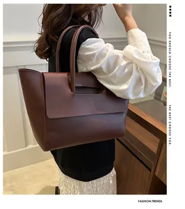 Detail of dark brown leather tote bag with flap closure shown worn as a shoulder bag