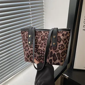 Close-up of leopard print tote bag featuring black handles and gold stud details