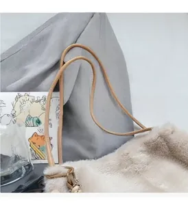 Detail of soft plush tote bag featuring durable brown leather handles and metal hardware