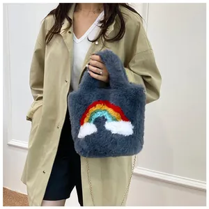 Detail of plush grey tote bag featuring rainbow embroidery and gold chain strap