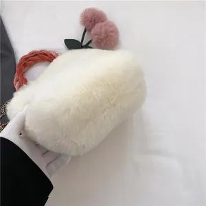 Detail of plush faux fur handbag featuring soft cherry pom-poms and woven pink handle