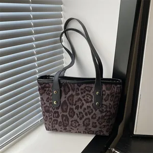 Macro detail of leopard print tote bag fabric with leather strap and gold rivet accents